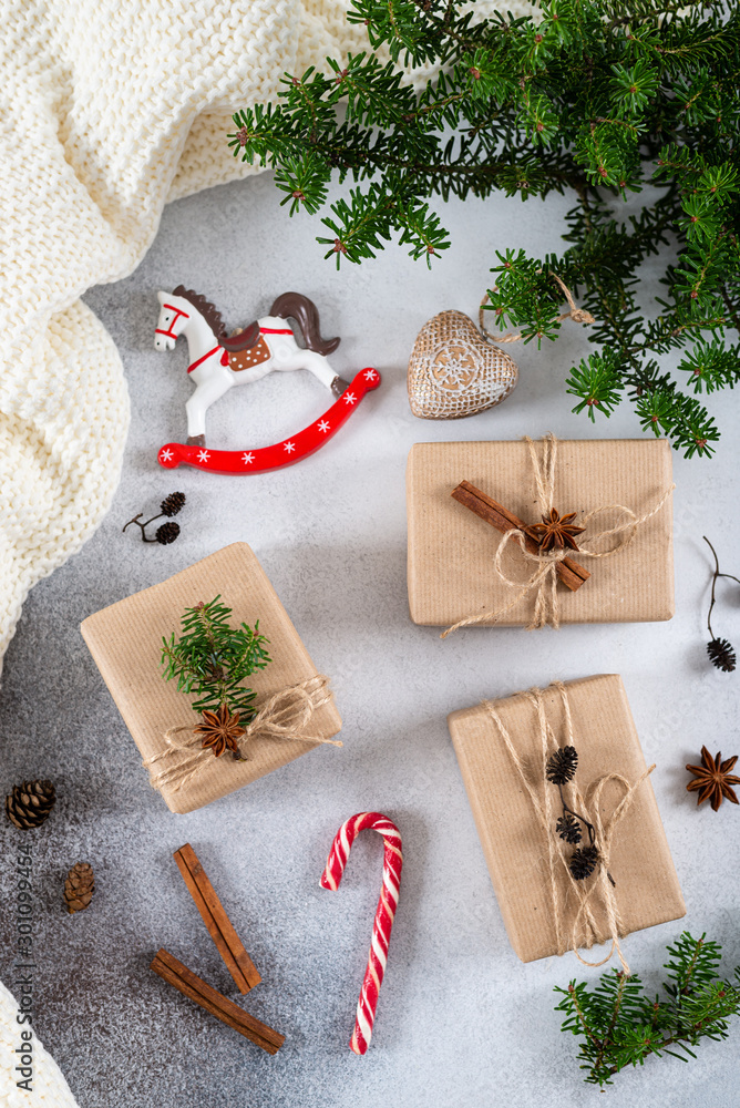 Obraz premium Christmas composition. Christmas gifts, knitted blanket, pine cones, fir branches on concrete gray background. Flat lay, top view