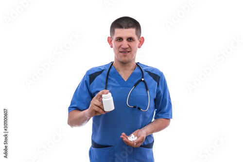 young doctor in blue uniform takes pills from jars isolated on white background