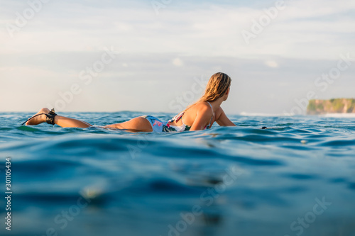 Attractive surfer girl on a surfboard in ocean.