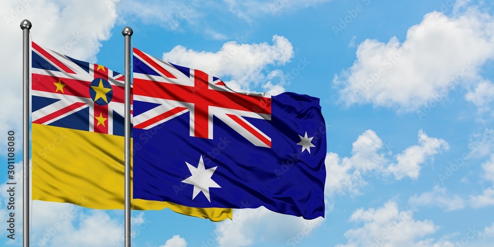 Niue and Heard Island and Mcdonald Islands flag waving in the wind against white cloudy blue sky together. Diplomacy concept, international relations.