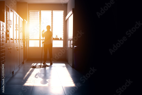 Wallpaper Mural Janitor woman mopping floor in hallway office building or walkway after school or classroom with copy space. Silhouette housekeeper working job with sun light background. Torontodigital.ca