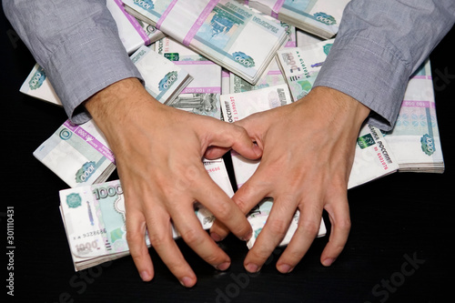 men's hands reach for wad of money. A million rubles on the black table. The concept of wealth, success, greed and corruption, lust for money photo