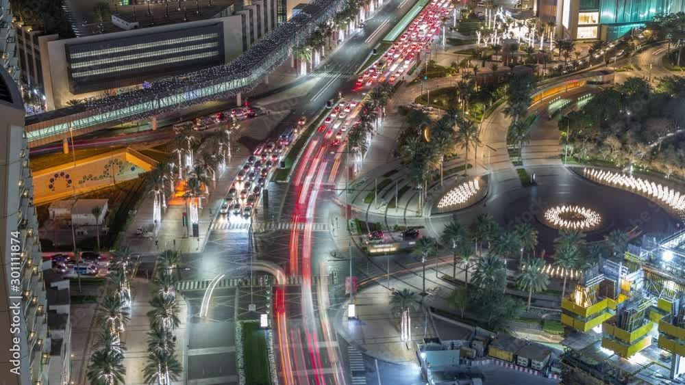 Aerial view of intersection with many transports in traffic and modern walking alley with fountain night timelapse in Dubai Downtown, Dubai, United Arab Emirates Aerial view of intersection with many transports in traffic and modern walking alley with fountain night timelapse in Dubai Downtown, Dubai, United Arab Emirates