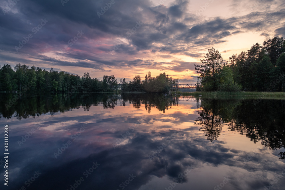 Dramatic clouds and sunset with beautiful lake reflection at summer evening in Finland