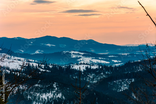 Winter tranquil stretched mountain landscape and the Carpathian mountain range behind. © Niko_Dali