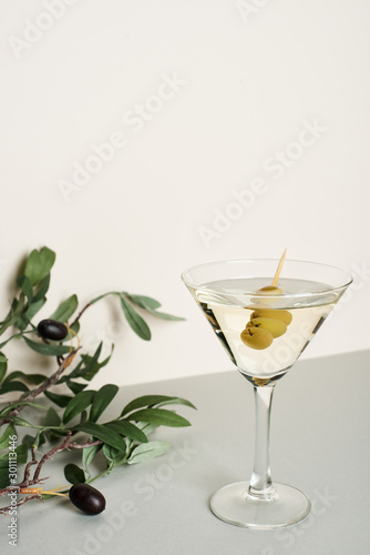 Martini cocktail with olive branch on white background