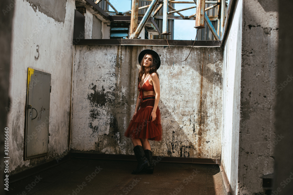 beautiful fashionable woman posing in red skirt, bra and hat on roof beautiful fashionable woman posing in red skirt, bra and hat on roof