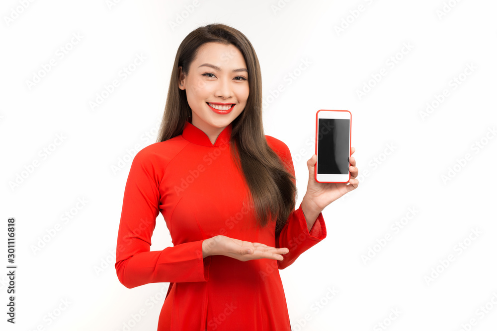 Naklejka premium Attractive woman in ao dai dress showing screen mobile phone, isolated on white background