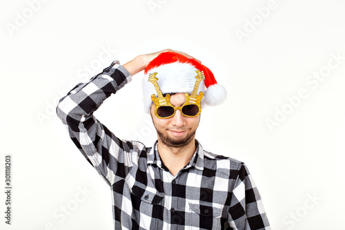 Portrait of a funny young man in Santa Claus hat and beard on white background. Christmas.