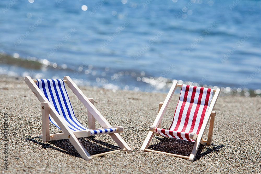 Toy chaise longue on sandy beach on sunny day at the blue sea background. Relaxation concept. Toy chaise longue on sandy beach on sunny day at the blue sea background. Relaxation concept.