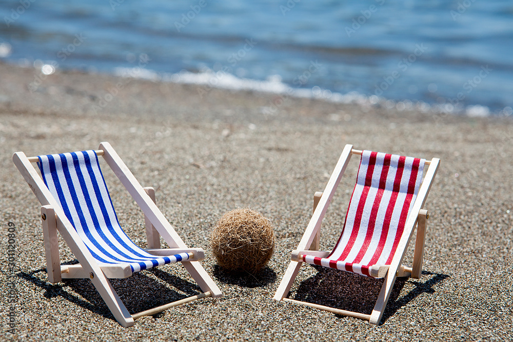 Toy chaise longue on sandy beach on sunny day at the blue sea background. Relaxation concept. Toy chaise longue on sandy beach on sunny day at the blue sea background. Relaxation concept.