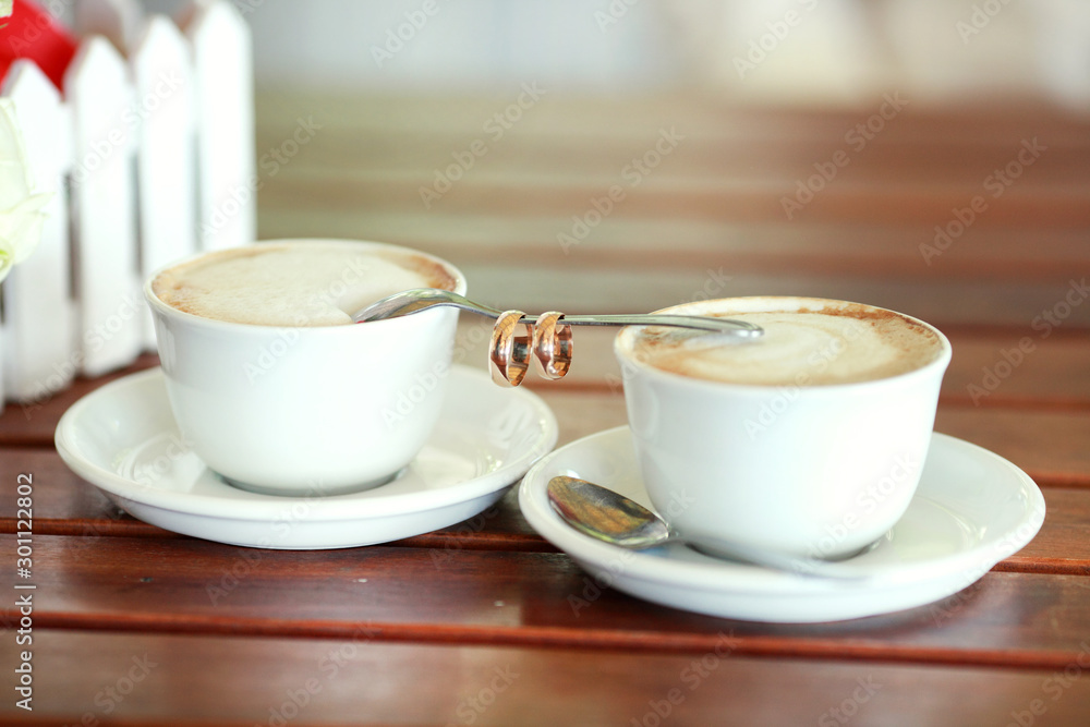 Bride and groom's Coffee time, coffee break.Cups and rings on teaspoon in cafe