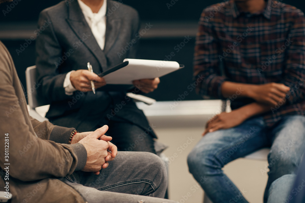 Close-up of people sitting on chairs and planning work together in team Close-up of people sitting on chairs and planning work together in team