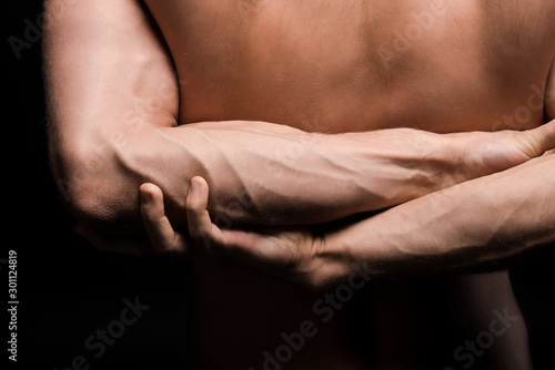 cropped view of muscular man with hands behind the back, isolated on black
