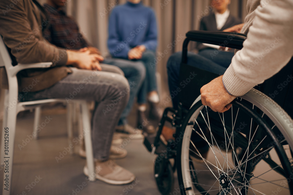 Obraz premium Close-up of senior disabled man sitting in wheelchair and visiting business meeting
