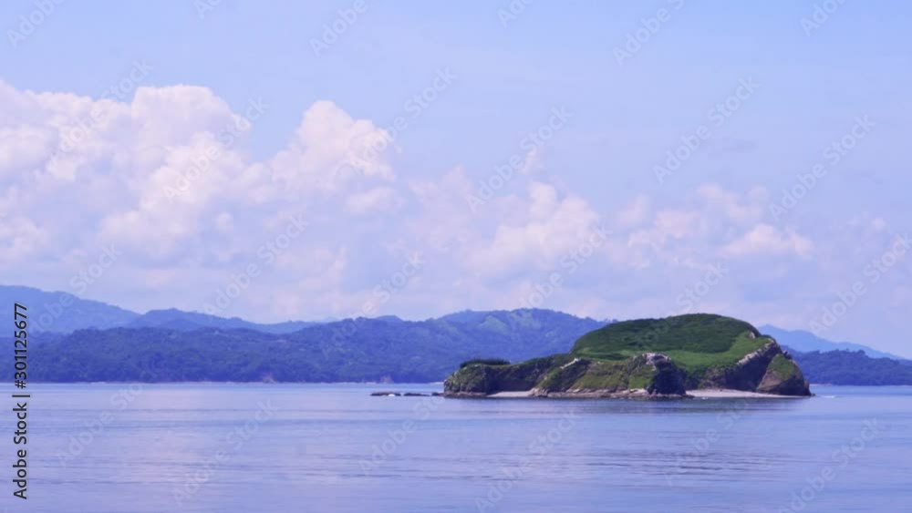 Passing Island with Mountains on the Horizon in Costa Rican Landscape on Sunny Day with cloudy Sky, Close Shot Passing Island with Mountains on the Horizon in Costa Rican Landscape on Sunny Day with cloudy Sky, Close Shot