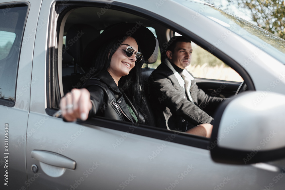 Happy Traveling Couple Dressed in Black Stylish Clothes Enjoying a Road Trip Sitting Inside the Car, Vacation Concept