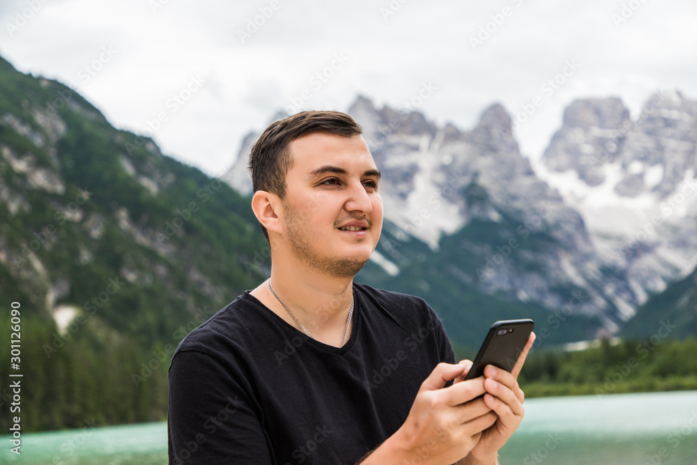 Young handsome man walking near beautiful lake using phone communicate with friends Young handsome man walking near beautiful lake using phone communicate with friends