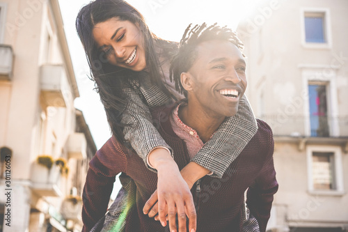 African couple having fun outdoor in city tour - Young people lovers enjoying time together during vacation journey - Love, fashion, travel and relationship concept - Focus on woman face