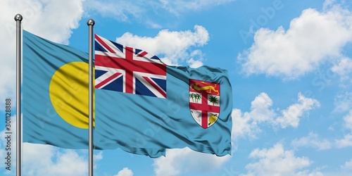 Palau and Fiji flag waving in the wind against white cloudy blue sky together. Diplomacy concept, international relations.