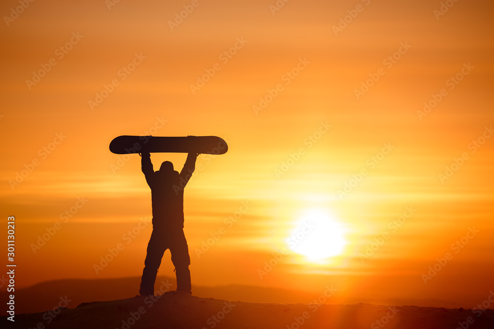 Snowboarder hold snowboard on background of sunset