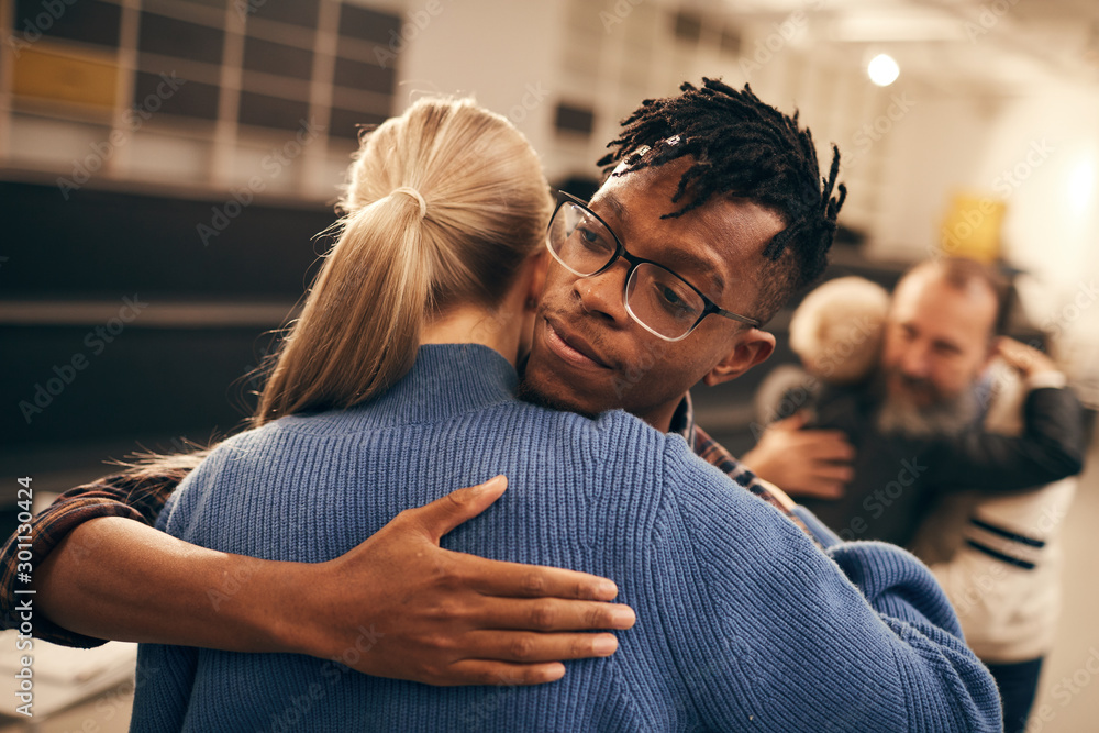Young African man in eyeglasses embracing the young woman and enjoying the process during therapy lesson
