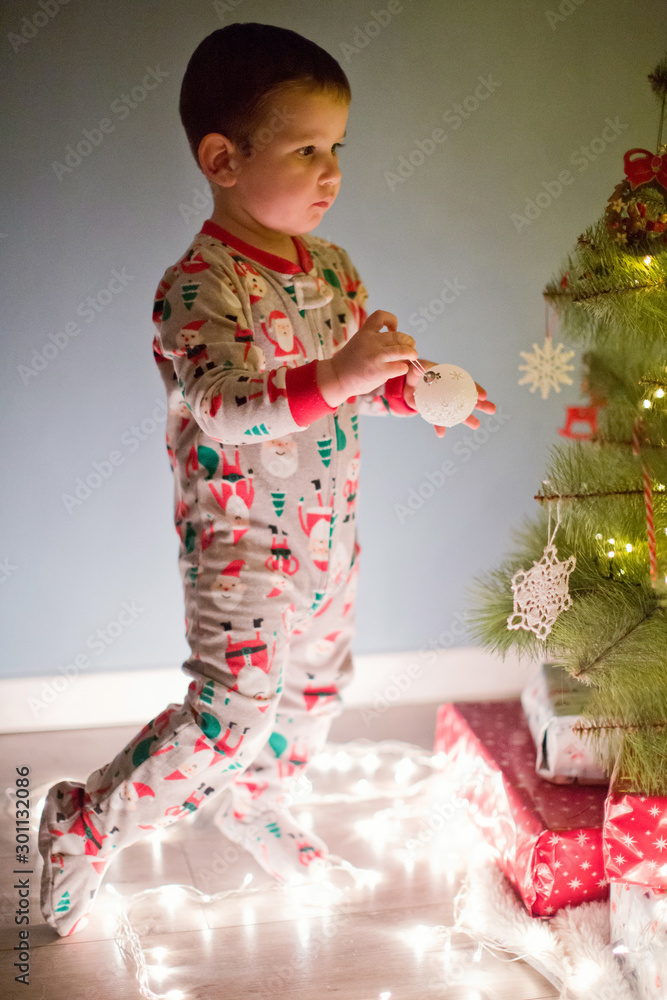 happy little boy in pyjamas decorate Christmas tree happy little boy in pyjamas decorate Christmas tree