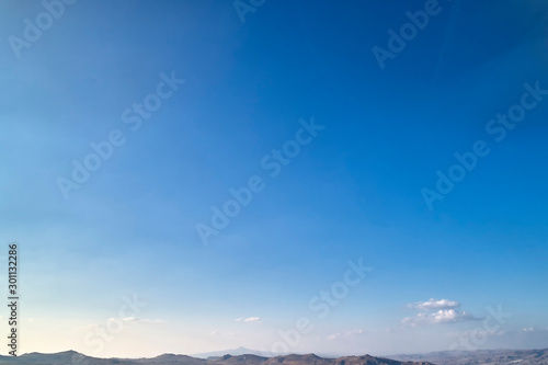 Bright autumn blue sky with white clouds and mountains at the horizon. Background or texture image with copyspace