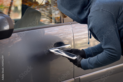 Hooded thief tries to break the car's security systems with tablet