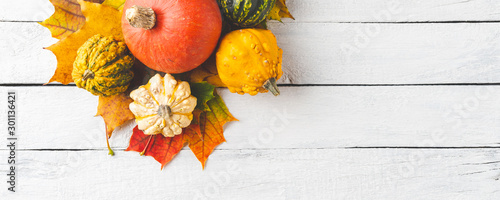 Composition of autumn leaves and pumpkins on white wooden table. Thanksgiving concept. Banner