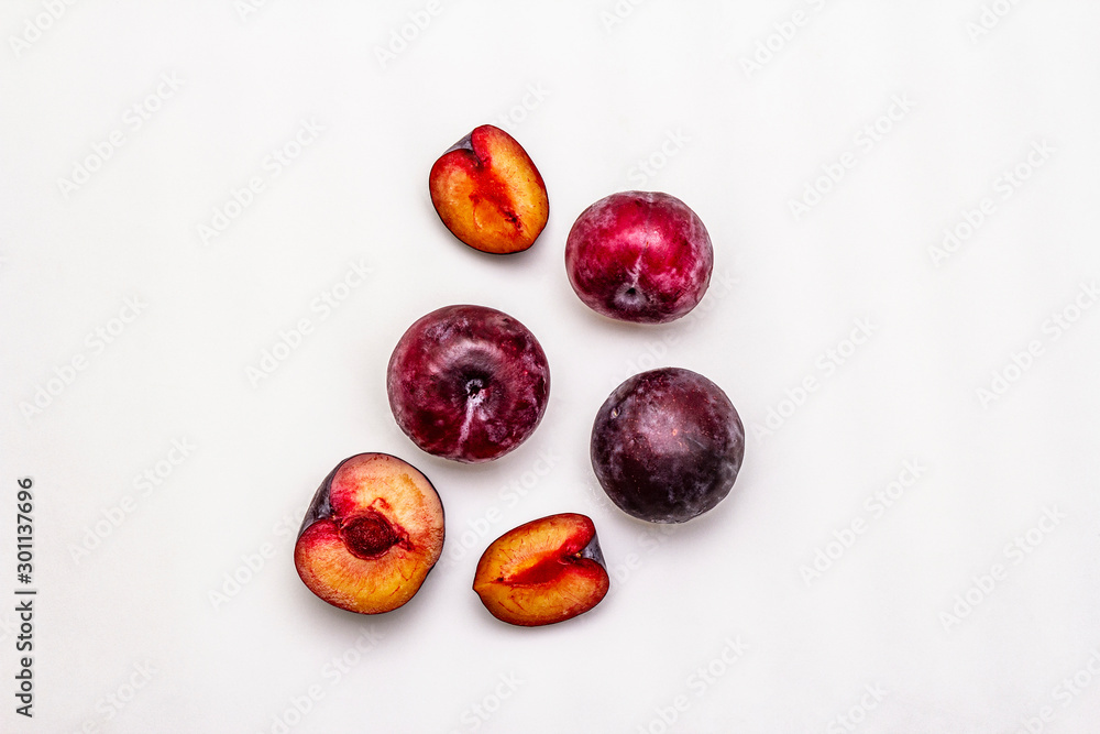 Ripe large purple plums. Fresh whole fruits, half sliced, seeds. Isolated on white background