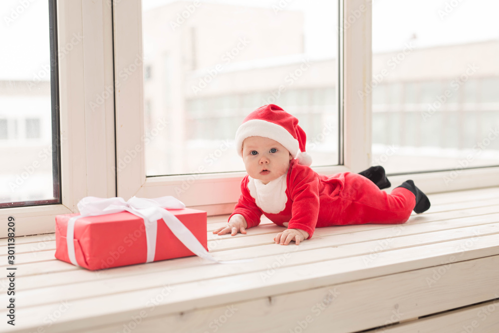 Beautiful little baby celebrates Christmas. New Year's holidays. Baby in a Christmas costume and in santa hat Beautiful little baby celebrates Christmas. New Year's holidays. Baby in a Christmas costume and in santa hat