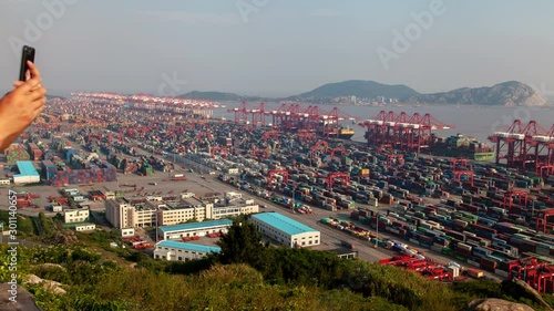 Timelapse tremendous container terminal area in Yangshan Port of Shengsi with Shanghai industrial constructions against hills silhouettes in China photo