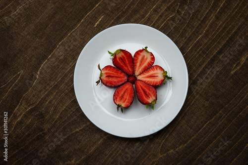 Strawberries on a white plate on a wooden table. creeative background concept.  - Image photo