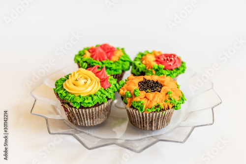Colorful cupcakes in a paper cases decorated with whipped cream. Floral muffins on white background.