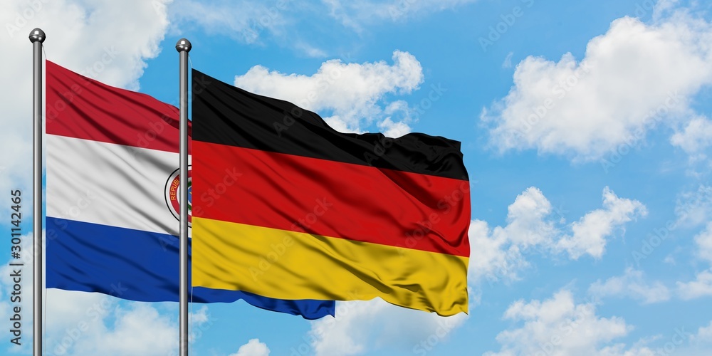 Paraguay and Germany flag waving in the wind against white cloudy blue sky together. Diplomacy concept, international relations. Paraguay and Germany flag waving in the wind against white cloudy blue sky together. Diplomacy concept, international relations.