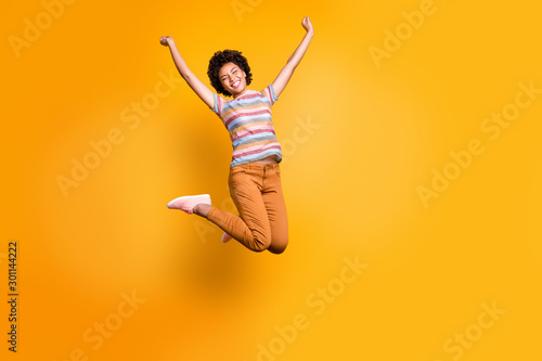 Full length body size photo of cheerful rejoicing curly wavy casual beautiful youngster ecstatic about buying new orange trousers striped t-shirt isolated bright color background © deagreez