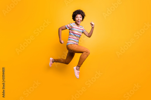 Full body profile photo of jumping high dark skin wavy lady speed race running champion wear casual summer clothes isolated bright yellow color background