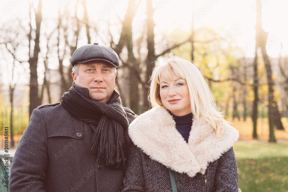 Closeup portrait of happy blonde mature woman and beautiful middle-aged brunette, looking looking directly at camera. Loving couple of 45-50 years old walks in autumn park in warm clothes Closeup portrait of happy blonde mature woman and beautiful middle-aged brunette, looking looking directly at camera. Loving couple of 45-50 years old walks in autumn park in warm clothes