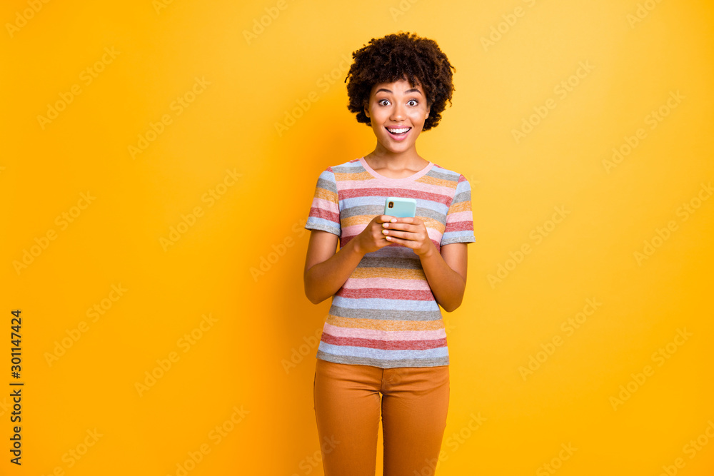 Photo of wavy curly cheerful cute charming fun girl wearing striped t-shirt orange pants trousers excited about notification received isolated over vivid color background Photo of wavy curly cheerful cute charming fun girl wearing striped t-shirt orange pants trousers excited about notification received isolated over vivid color background