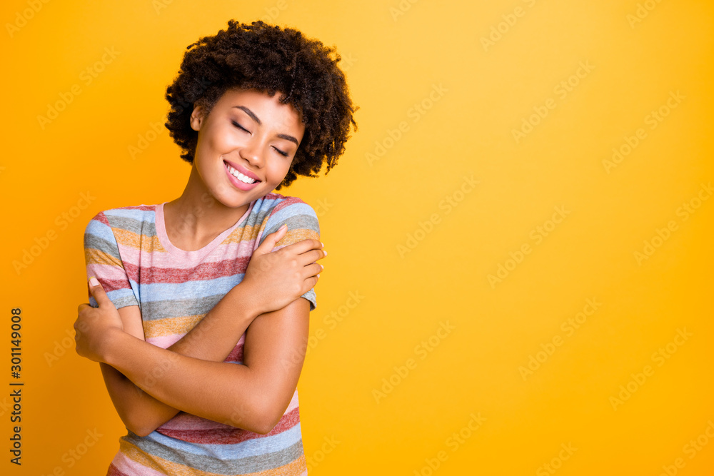 Photo of cheerful cute nice attractive youngster in her embrace enjoying comfortable striped t-shirt near empty space with toothy smile isolated over bright color background Photo of cheerful cute nice attractive youngster in her embrace enjoying comfortable striped t-shirt near empty space with toothy smile isolated over bright color background