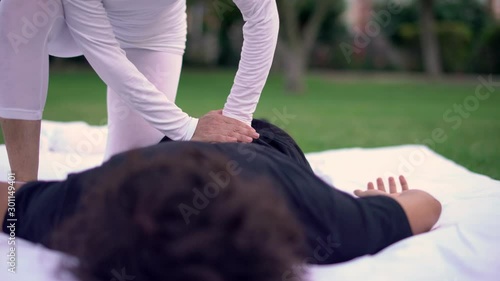 Overhead of young man guy lying facedown while his back and shoulders being massaged by a Shiatsu masseuse. Backache. Shiatsu treatments for healthy life wellbeing. Cine lens. photo