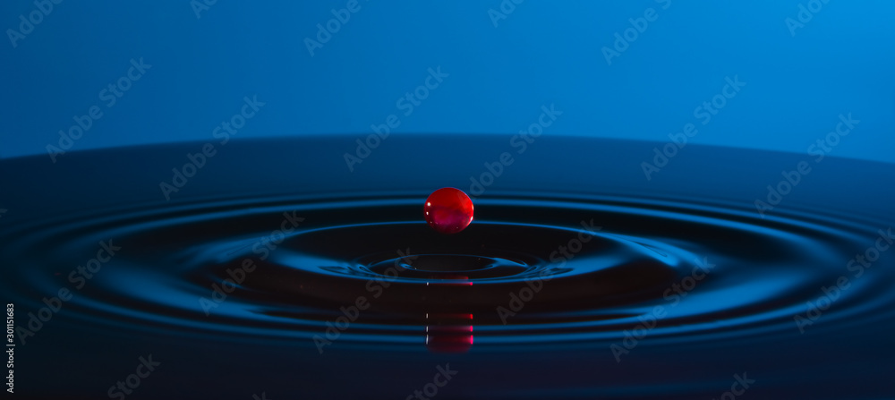 Red drop of water and circles on the water on blue background. Red drop of water and circles on the water on blue background.