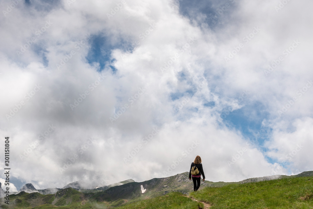 A young hiker walks through the Pyrenees Mountains in France, near the Pic du Midi d'Ossau massif.