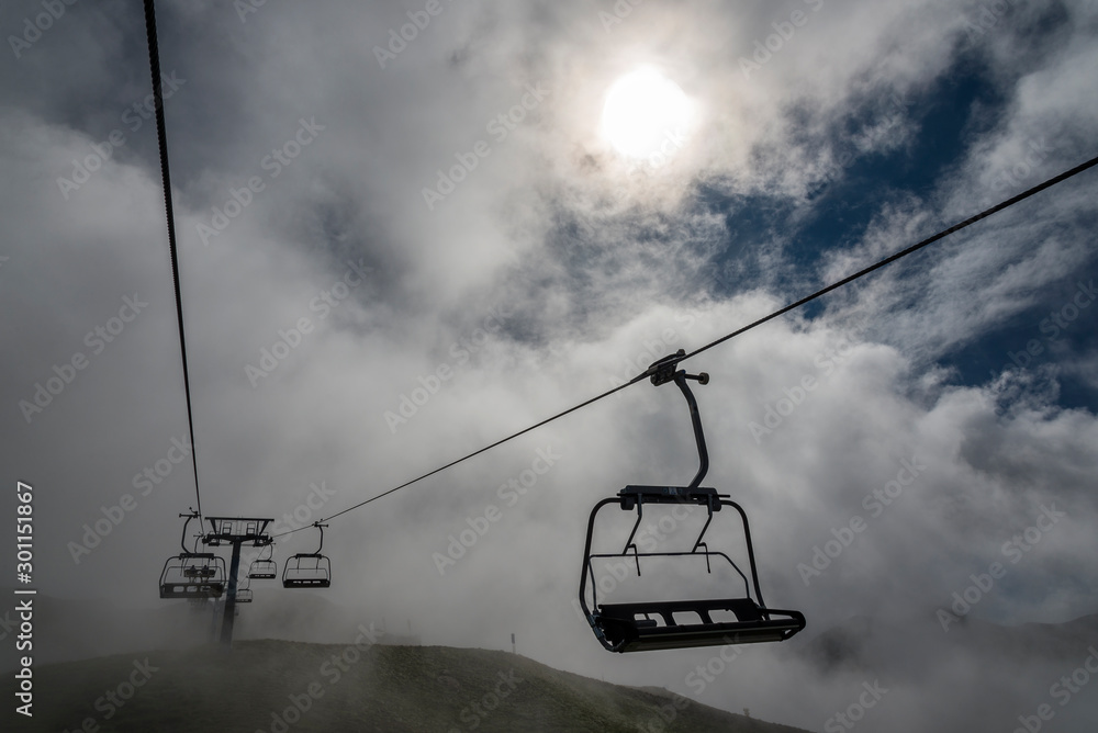 Image of a chairlift emerging from a sea of clouds in the Pyrenees Mountains (Spain).