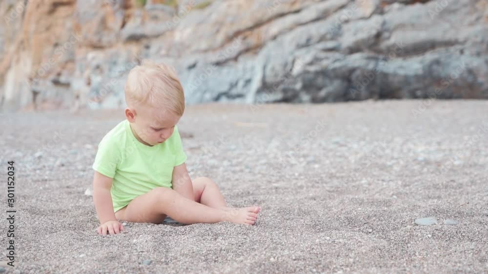 Little boy on the beach is playing with sand