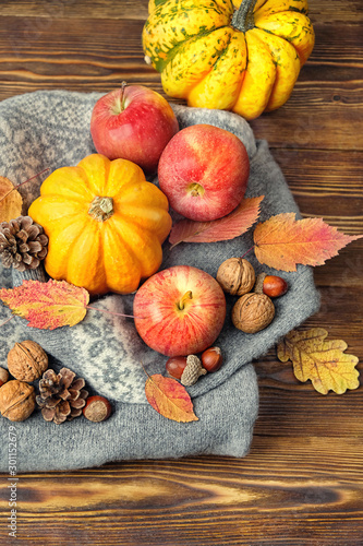 autumn composition with pumpkins, cones, nuts, apples and sweater on wooden table background. fall season, thanksgiving holiday concept. top view