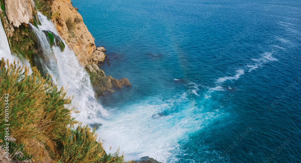 Beautiful big waterfalls falling down into vivid blue water of Mediterranean sea. Horizontal color photography.