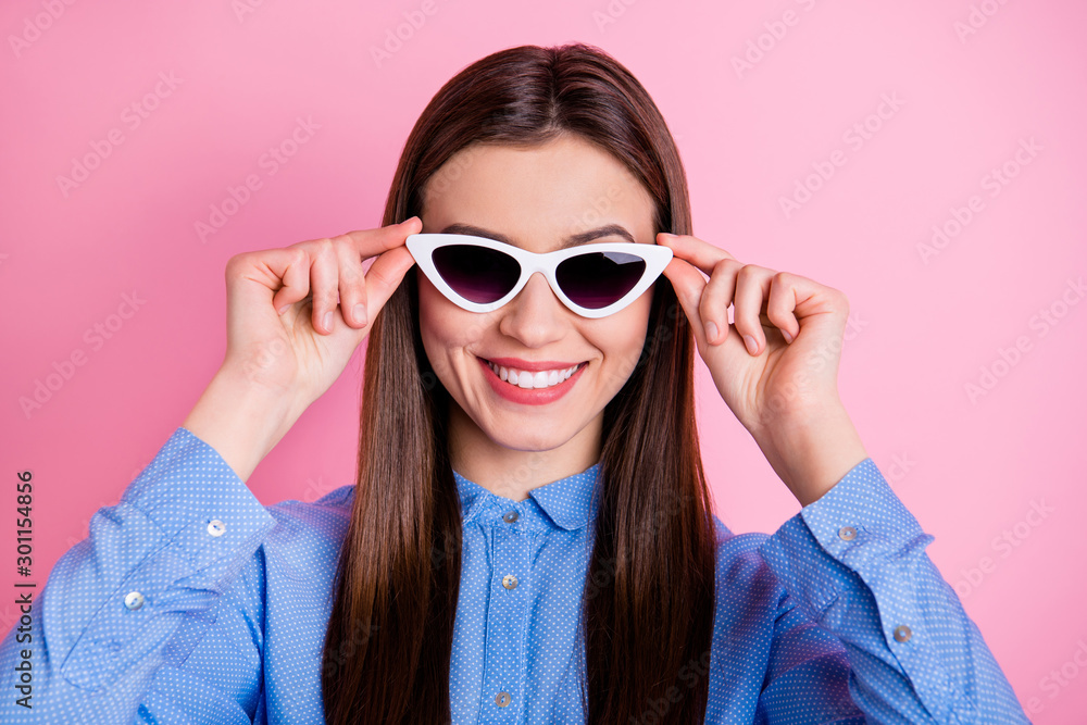 Close up photo of cute nice fascinating good lady wearing sunglass eyewear holding them with hands smiling toothily isolated over pink pastel color background Close up photo of cute nice fascinating good lady wearing sunglass eyewear holding them with hands smiling toothily isolated over pink pastel color background