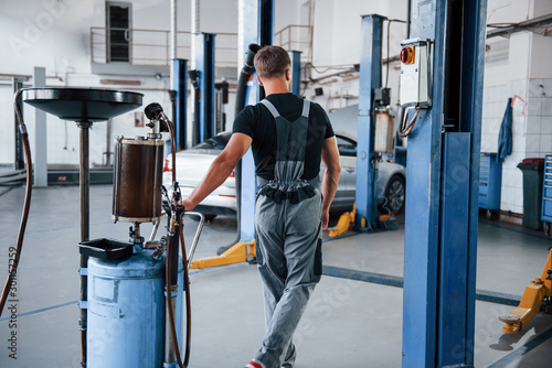 Problem will be solved soon. Male mechanic use special device to repair broken automobile in garage